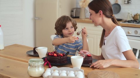 Mother and son eat cake boy feeds happy mom with strawberry