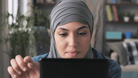 close portrait of arab woman holding tablet browsing social media network indoor,headshot front view of young muslim female wearing hijab using touch screen device searching online,internet indoors
 - Powered by Shutterstock - Get 15% off with code: PIKWIZARD15