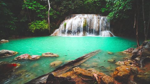 Waterfalls and fish swim in the emerald blue water in Erawan National Park. Erawan Waterfall is a beautiful natural rock waterfall in Kanchanaburi, Thailand.Onsen atmosphere. soft focus.