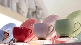 different-colored porcelain cups are on the counter of the store. dolly video