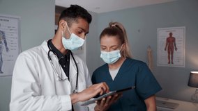Male and female doctors standing in office reading information from digital tablet