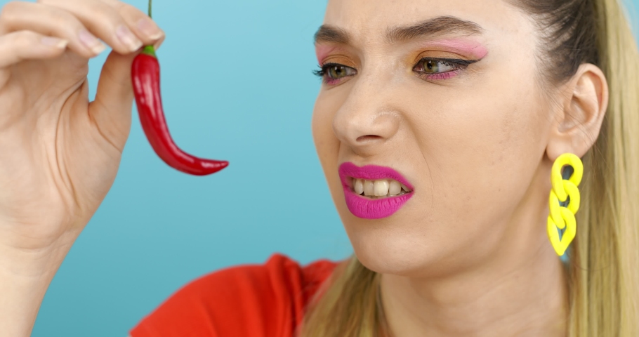 Young woman tastes red chili. The girl bites the pepper.