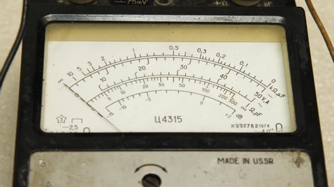 The hand runs on the dial of an old analog multimeter. The device is designed to measure DC and AC current, voltage and resistance. Repair shop for electronics, computers, phones and TV
