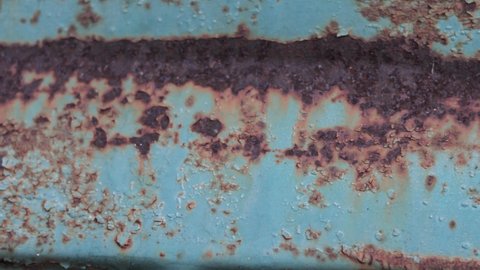 Rusty painted metal surface. Macro view of corrosion in iron metal, texture background. Smooth slow motion. 4k video footage
