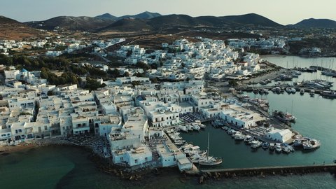 Aerial views of the traditional greek whitewashed houses with the blue windows and flowered yards in the touristic Naoussa town of Paros island in Greece.