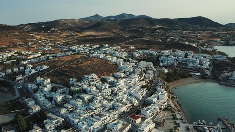Aerial views of the traditional greek whitewashed houses with the blue windows and flowered yards in the touristic Naoussa town of Paros island in Greece.