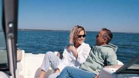 Young woman and man ride a speedboat. Hair fluttering in the wind. Adult couple enjoying summer vacation on the deck of a yacht. European Summer Holidays