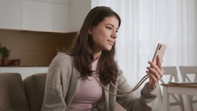 Young caucasian woman greeting her friends or family on a video call using pink smart phone