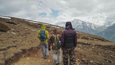 Tourist trekking down, wayback after mountain conquest against cloudy snowy Annapurna, Nepal