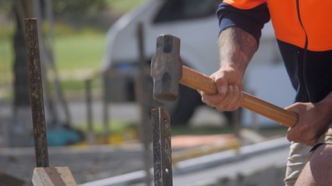 Ocean Grove , Victoria , Australia - 09 17 2021: Construction Worker Using Sledge Hammer To Drive Stake Into Ground