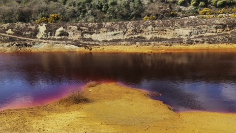 River of dark red chemicals from a mining site in Cornwall, England -Wide
