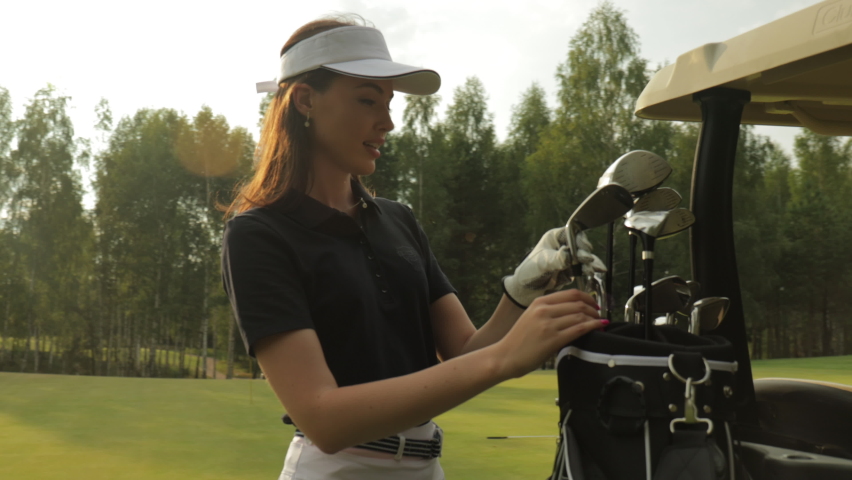 Professional woman golf player choosing the golf club from the bag.