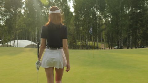 Young woman on golf course, back view.