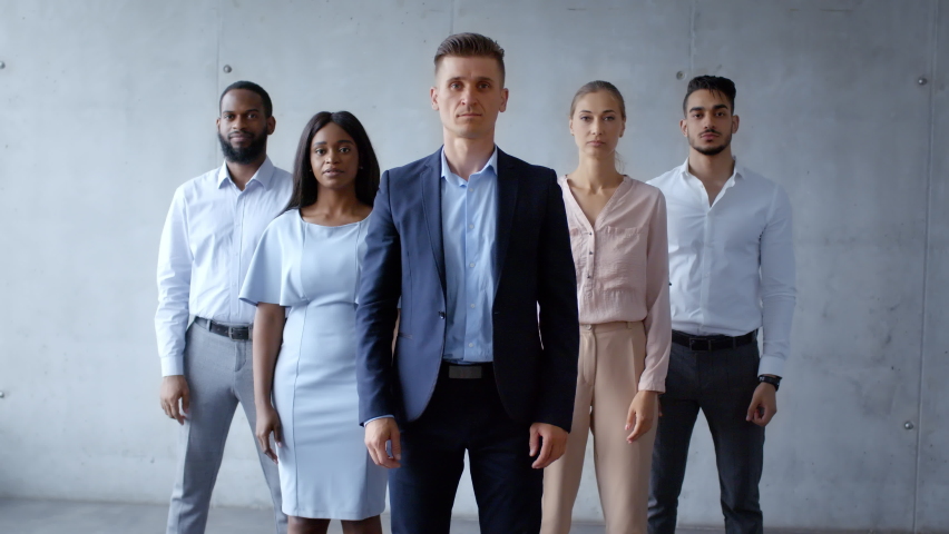 Professional business team. Group of confident diverse colleagues headed with boss folding arms, posing to camera over grey wall in office, slow motion Royalty-Free Stock Footage #1079426855
