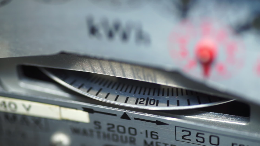 Macro close-up of a domestic electric meter and slow turning measuring dial. Concept for energy, utility bills, price rise, meter reading, inflation and cost of living. Static shot. Royalty-Free Stock Footage #1079431259