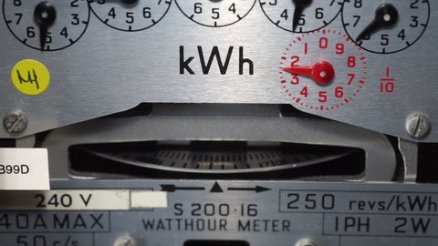 Macro close-up of a domestic kWh electric meter and slow turning measuring dial. Concept for energy, utility bills, price rise, meter reading, inflation and cost of living. Static shot.