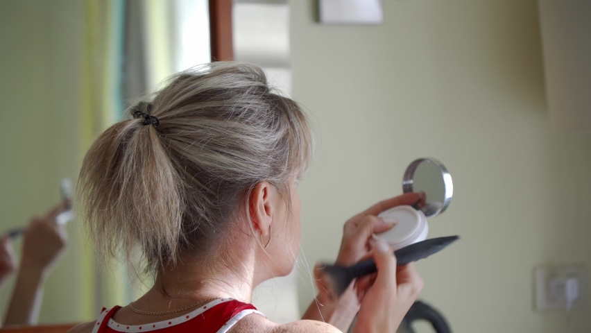 A middle-aged woman does daily makeup at home in the morning. Hide blemishes on the face with makeup. Royalty-Free Stock Footage #1079434673