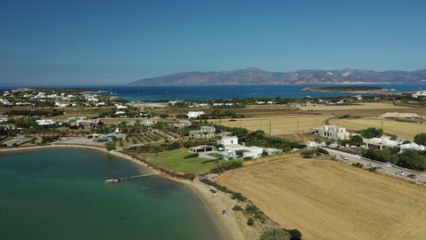 Aerial landscape of Paros island in Greece. Coastline with crystal clear turquoise Aegean sea waters, beaches, villages and tiny islands. Blue skies and mountains in the background.