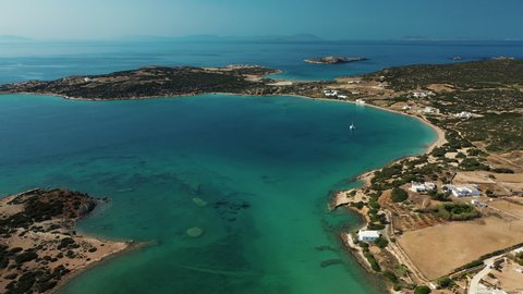 Aerial landscape of Paros island in Greece. Coastline with crystal clear turquoise Aegean sea waters, beaches, villages and tiny islands. Blue skies and mountains in the background.