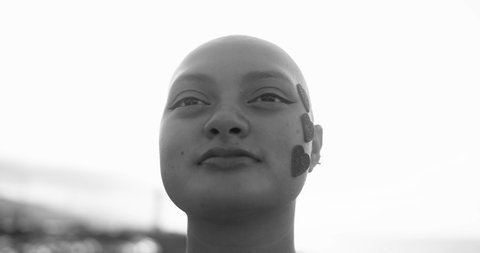 Young bald girl with heart stickers on her face posing in front of camera at sunset - Black and white editing