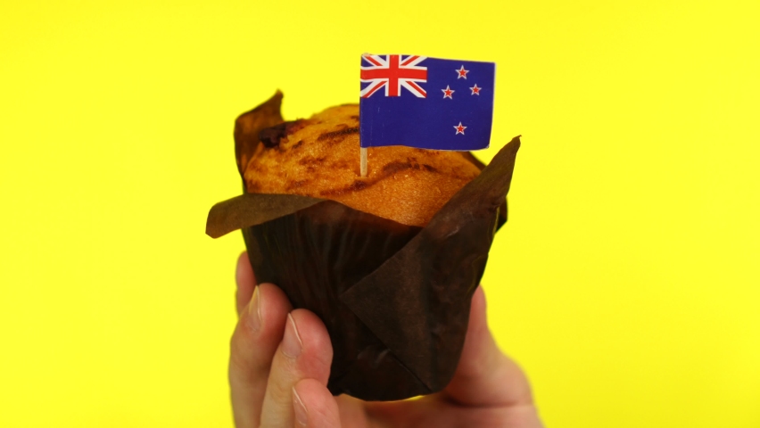 Cupcake with New zealand flag on male palm against yellow background