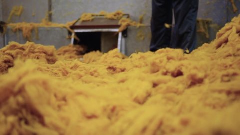 Slow motion HD 50 fps shot of workers in a wool factory sweeping yellow wool in a store room. The footage was captured in an industrial wool factory, producing textiles and cotton in bullk.
