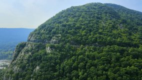 Aerial drone video footage of an Appalachian mountain river valley with a beautiful domed mountain with a road. This is storm king mountain in new York's Hudson river valley.
