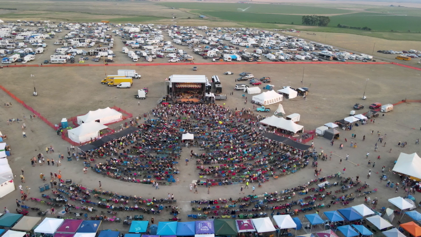 Marquee and tents selling hot food and drinks at an outdoor live country music festival.