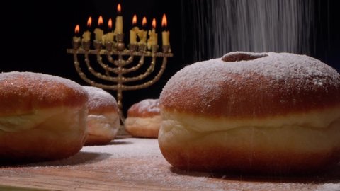The Hanukkah menorah and lights. Sufganiyot are fried balls of yeast dough filled with strawberry jelly and dusted heavily with powdered sugar. Cooking of doughnuts