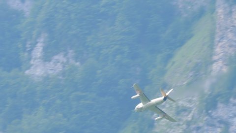 Mollis Switzerland AUGUST, 16, 2019 Vintage jet fighter plane silhouette flying in a beautiful green alpine valley surrounded by rock faces. Hawker Hunter vintage fighter jet of Swiss Air Force in 4K