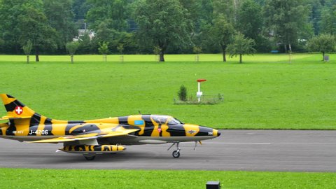 Mollis Switzerland AUGUST, 16, 2019 Combat aircraft in yellow and black tiger livery taxies on the airport runway to take off. Hawker Hunter vintage fighter jet of Swiss Air Force in 4K