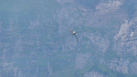 Mollis Switzerland AUGUST, 16, 2019 Combat fighter jet of cold era flies fast in a narrow mountain valley. Hawker Hunter two seats transonic aircraft of Swiss Air Force in tiger livery