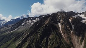 Steep rocky mountains with cliffs and ledges, covered with snow and clouds. Mount Elbrus, video filming from a quadcopter in the daylight