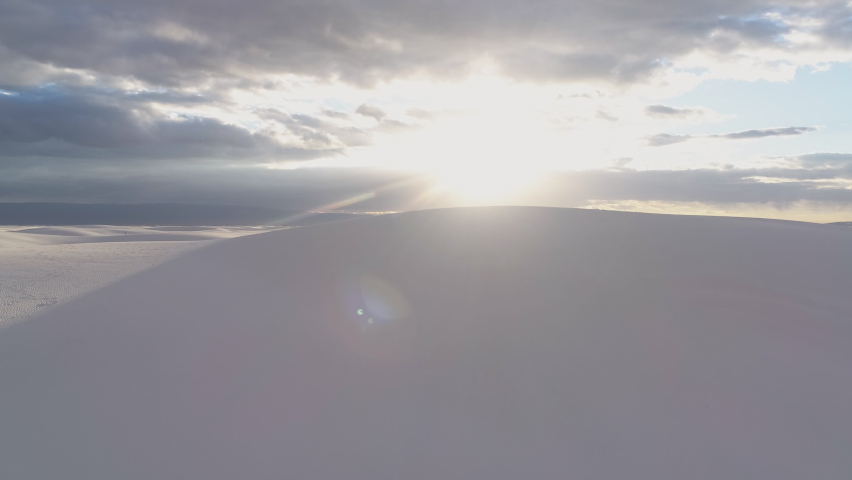 4K aerial coming over dune to reveal vast white sand dune field at sunrise