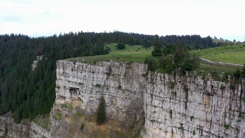 Rotating drone shot of the cliff walls at Creux du Van in Switzerland, located at the border of the cantons of Neuenburg and Vaud
