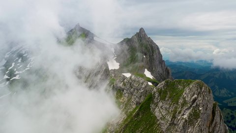 Cinematic rotating drone shot of Altenalp Turm, with clouds on one side of the mountain. Located in the canton of Appenzell Innerrhoden in Switzerland.
