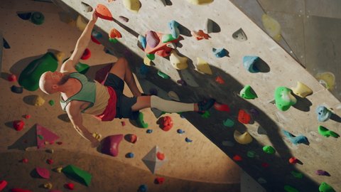 Strong Experienced Rock Climber Practicing Solo Climbing on Bouldering Wall in Gym. Man Exercising at Indoor Fitness Facility, Doing Extreme Sport for His Healthy Training. Lifestyle Portrait.