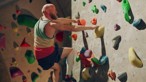 Strong Experienced Rock Climber Practicing Solo Climbing on Bouldering Wall in Gym. Man Exercising at Indoor Fitness Facility, Doing Extreme Sport for His Healthy Training. Lifestyle Portrait.