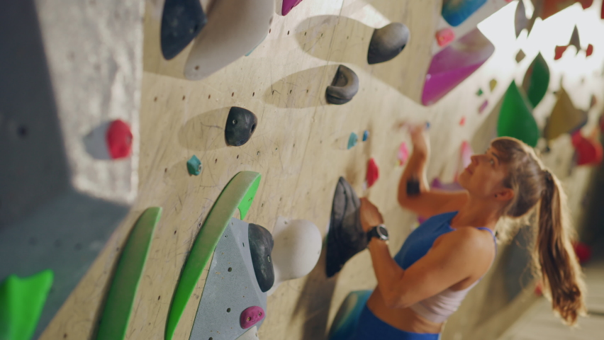 Athletic Female Rock Climber Practicing Solo Climbing on Bouldering Wall in Gym. Female Exercising at Indoor Fitness Facility, Doing Extreme Sport for Her Healthy Lifestyle Training. Close Up Portrait Royalty-Free Stock Footage #1079475185