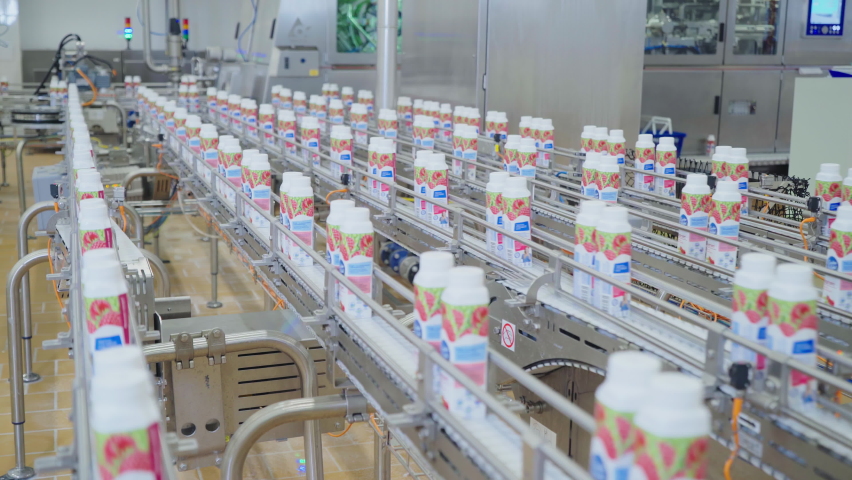 Multiple packages of dairy food items are moving on a conveyor line at the factory. Bottles with milk are advancing on the factory conveyor at a dairy plant. Production conveyor belt at dairy factory. Royalty-Free Stock Footage #1079478632