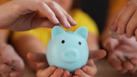Close-up of hand throwing coins into piggy bank. Financial and business safety. Coins in piggy bank symbol of bank safety. Financial savings are kept in bank. Business and financial safety concept