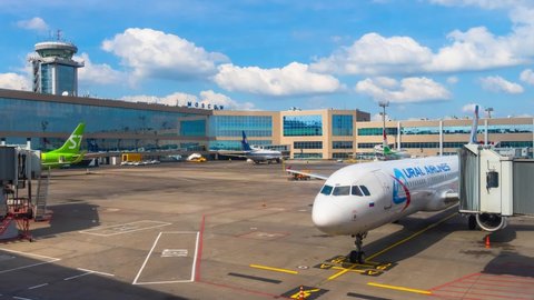Moscow, Russian Federation - May 19, 2021: Timelapse footage of domodedovo airport terminal with planes and ground crew doing their work. There are buildings and vehicles on asphalt field with blue