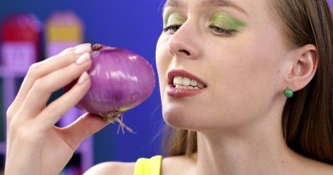 Sad girl eating nasty onion. The young woman grimaces at the smell.