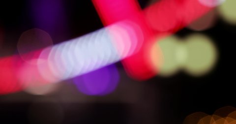 Abstract bokeh background, colourful night city lights. Moving defocused lights. Festival Event Party, fun atmosphere. Blurred ferris wheel multicolour night lights.