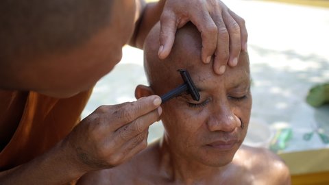 Thai monk shaving eyebrows to new monk outside temple. Close up. Ordaining ceremony a man take the tonsure to be a monk. Traditional Buddhist matriculation. Wat Pran Buri, Thailand 29 Jan 2016