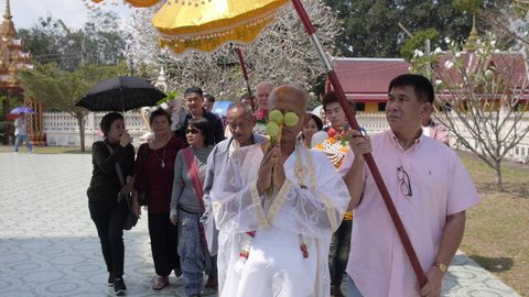 Thai monk in white clothes, his family and friends walking around temple. Ordaining ceremony a man take the tonsure to be a monk. Traditional Buddhist matriculation. Wat Pran Buri, Thailand 29 Jan 201