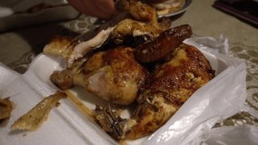 close-up of a grilled chicken in a plastic technopor taper serving with your hands on the living room table
