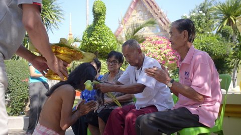 Thai family father cut hair to son monk outside temple put hair on leaf. Ordaining ceremony a man take the tonsure to be a monk. Traditional Buddhist matriculation. Wat Pran Buri, Thailand 29 Jan 2016