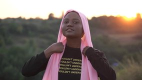 4k Video portrait of attractive muslim woman in black robe. Girl wearing pink scarf and posing and sunset.