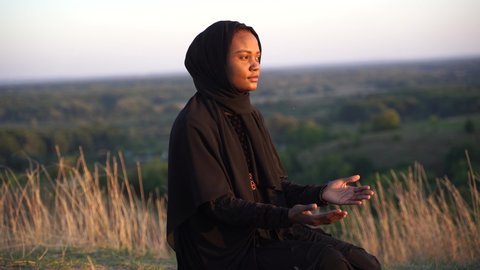 4k Black muslim woman praying on the carpet. Solat praying on the beautiful hill. Salah traditional pray.